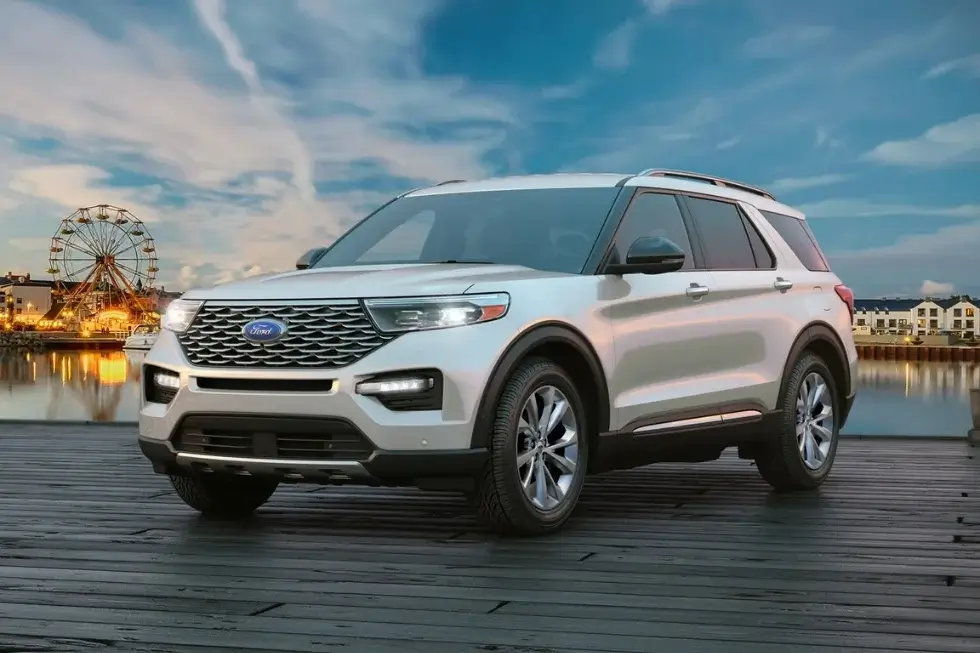 White Ford Explorer parked on a wooden dock with a Ferris wheel in the background