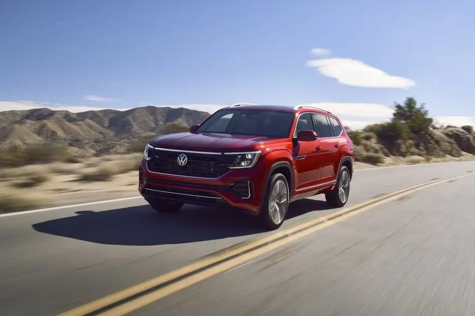 Red 2024 Volkswagen Atlas SUV driving down a desert road The Atlas is a mid-size SUV that offers optional second-row bench seating making it a versatile choice for families