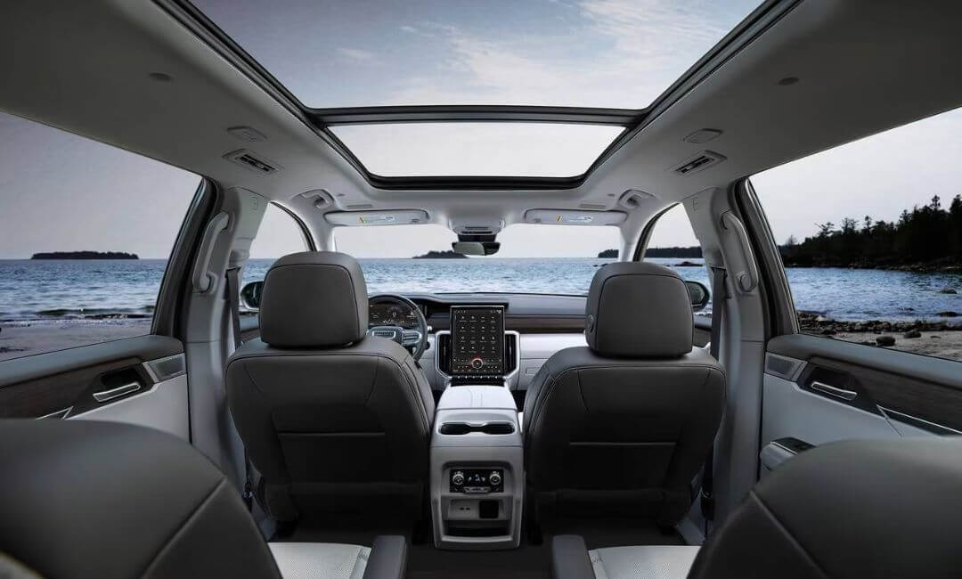 2025 GMC Acadia Denali interior view showing panoramic sunroof front seats and dashboard