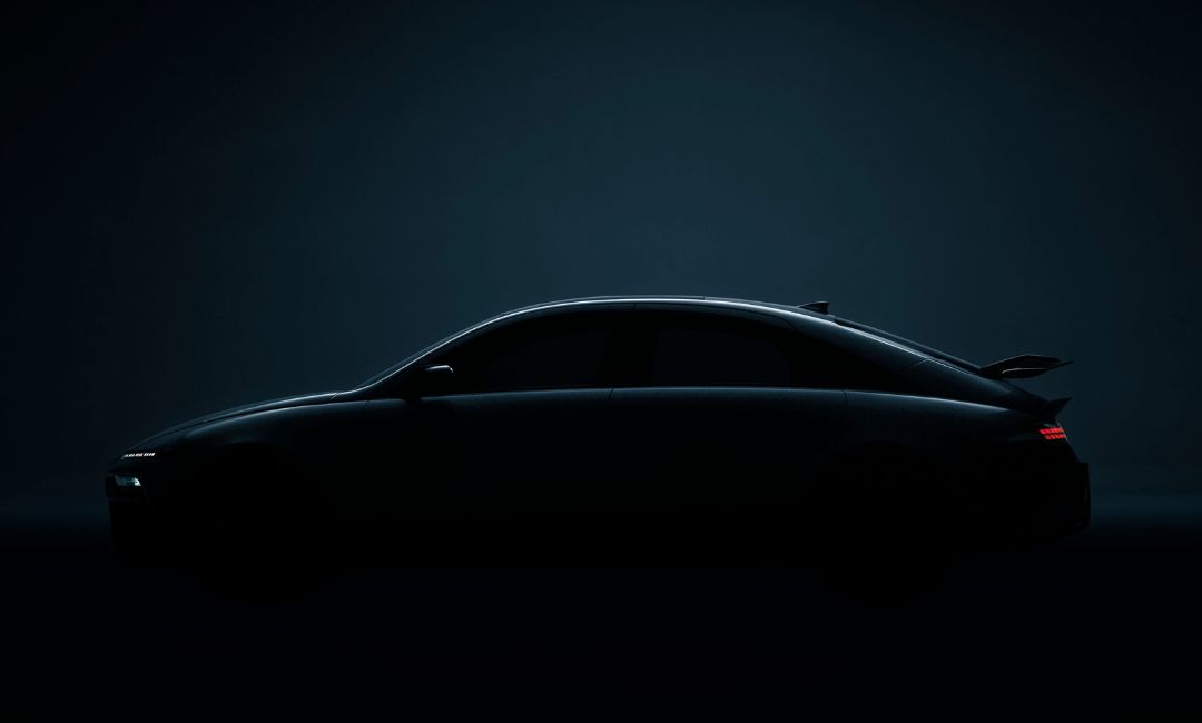 Side view teaser of the 2026 Hyundai Ioniq 6 N showcasing its sporty spoiler and sleek electric fastback design in low light