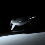Shadowy teaser image of the Acura RSX Prototype EV front view, showing sharp headlights and Acura emblem.